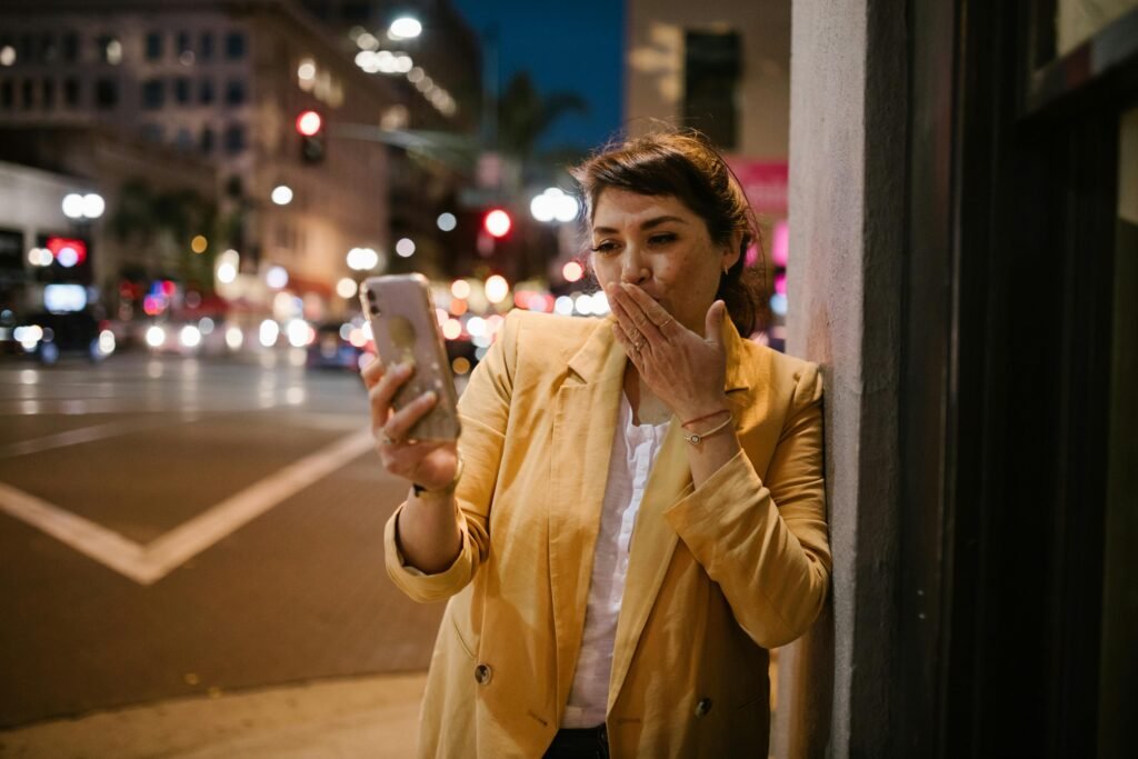 A woman engages in a cheerful video call on a vibrant city street at night.